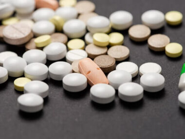 Heap of colorful medication on black table.