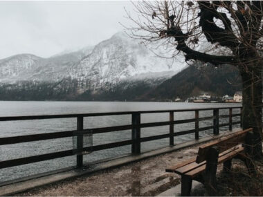 Bench near the lake on a cold day and snowy mountains