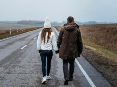 Back view of couple holding hands on the road