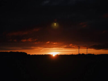 Wide shot of the silhouettes of hills in the countryside at sunset