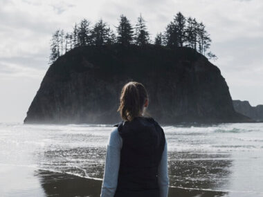 Back view of woman on shore with cliff