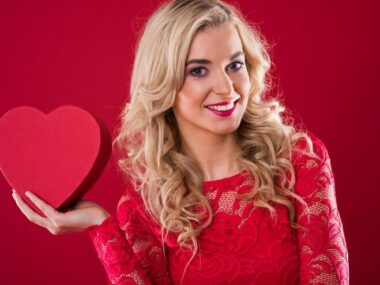 Smiling woman holding red heartshape box