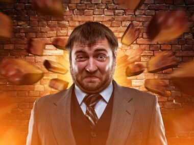 Surprised businessman against blowing brick wall