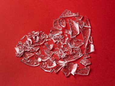 Top view broken glass heart on red background