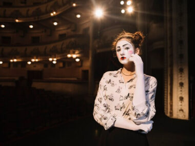 Contemplated female mime standing on stage in auditorium