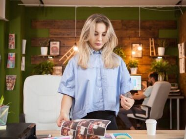 Creative female designer in her office with coworker in the background.