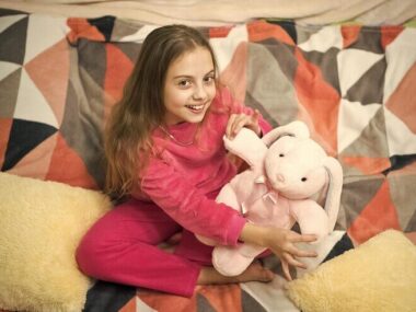 Little happy girl in bed with doll