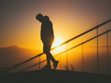 Silhouette of a young male walking on the staircase behind stair rails with beautiful sunset view