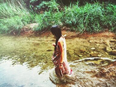 Full length side view of young woman standing in a lake