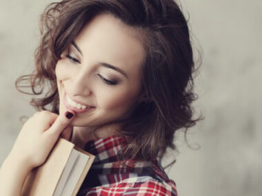 Beautiful girl smiling while having book in hand