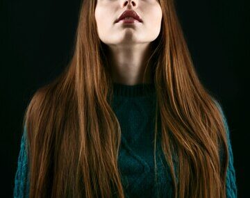 Woman with sensetive pink lips and long brown hair looks up in the sky