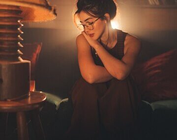 Young thoughtful woman in eyeglasses in a cozy living room