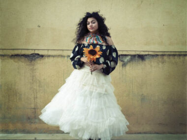 Elegant Woman Holding Sunflower Against Rustic Wall