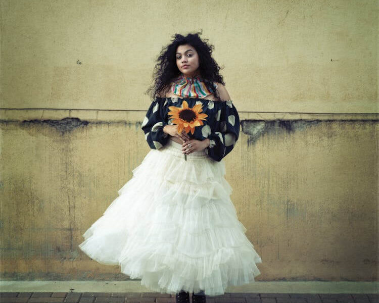 Elegant Woman Holding Sunflower Against Rustic Wall