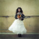 Elegant Woman Holding Sunflower Against Rustic Wall