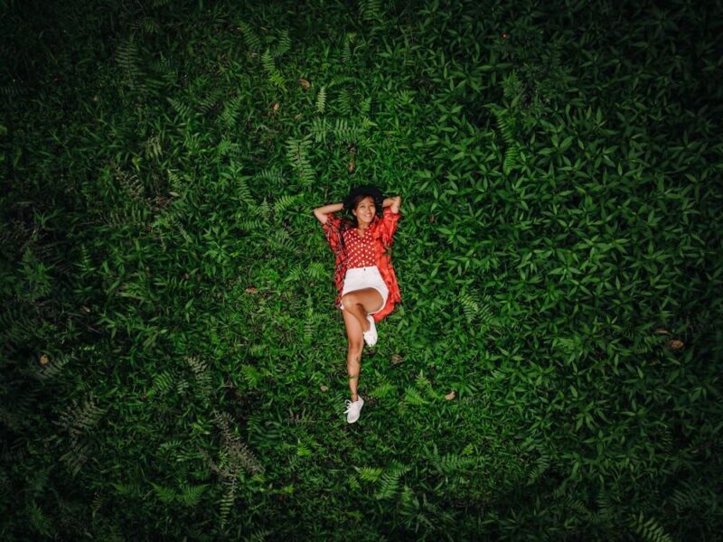 A Woman Lying Down on the Green Grass Field