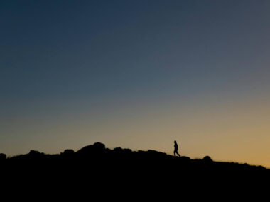 Silhouette of a Person Walking on a Hill in evening